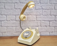 Load image into Gallery viewer, A quirky lamp made from a retro phone. The base of the lamp is a classic cream rotary phone with a mustard colored dial ring. The mustard handset mounted on a flexible gooseneck has a small LED bulb in the receiver converting it into a fabulous lamp.