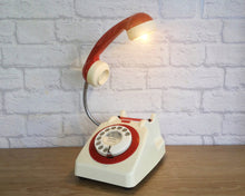 Load image into Gallery viewer, A quirky lamp made from a retro phone. The base of the lamp is a classic cream rotary phone with a cream dial & red dial ring. The red handset mounted on a flexible gooseneck has a small LED bulb in the receiver converting it into a fabulous lamp.