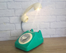 Load image into Gallery viewer, A quirky lamp made from a retro phone. The base of the lamp is a bright emerald green rotary phone with a cream dial ring. The cream handset mounted on a flexible gooseneck has a small LED bulb in the receiver converting it into a fabulous lamp.