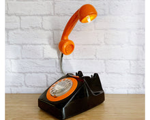 Load image into Gallery viewer, A quirky lamp made from a retro phone. The base of the lamp is a classic black rotary phone with a bright orange dial ring. The orange handset mounted on a flexible gooseneck has a small LED bulb in the receiver converting it into a fabulous lamp.