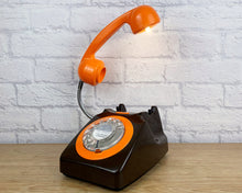 Load image into Gallery viewer, A quirky lamp made from a retro phone. The base of the lamp is a classic black rotary phone with an orange colored dial ring. The orange handset mounted on a flexible gooseneck has a small LED bulb in the receiver converting it into a fabulous lamp.