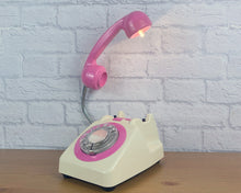 Load image into Gallery viewer, A quirky lamp made from a retro phone. The base of the lamp is a classic cream rotary phone with a hot pink dial ring. The hot pink handset mounted on a flexible chrome gooseneck has a small LED bulb in the receiver converting it into a unique lamp.