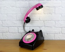 Load image into Gallery viewer, A quirky lamp made from a retro phone. The base of the lamp is a classic black rotary phone with a hot pink colored dial ring. The pink handset mounted on a flexible gooseneck has a small LED bulb in the receiver converting it into a fabulous lamp.
