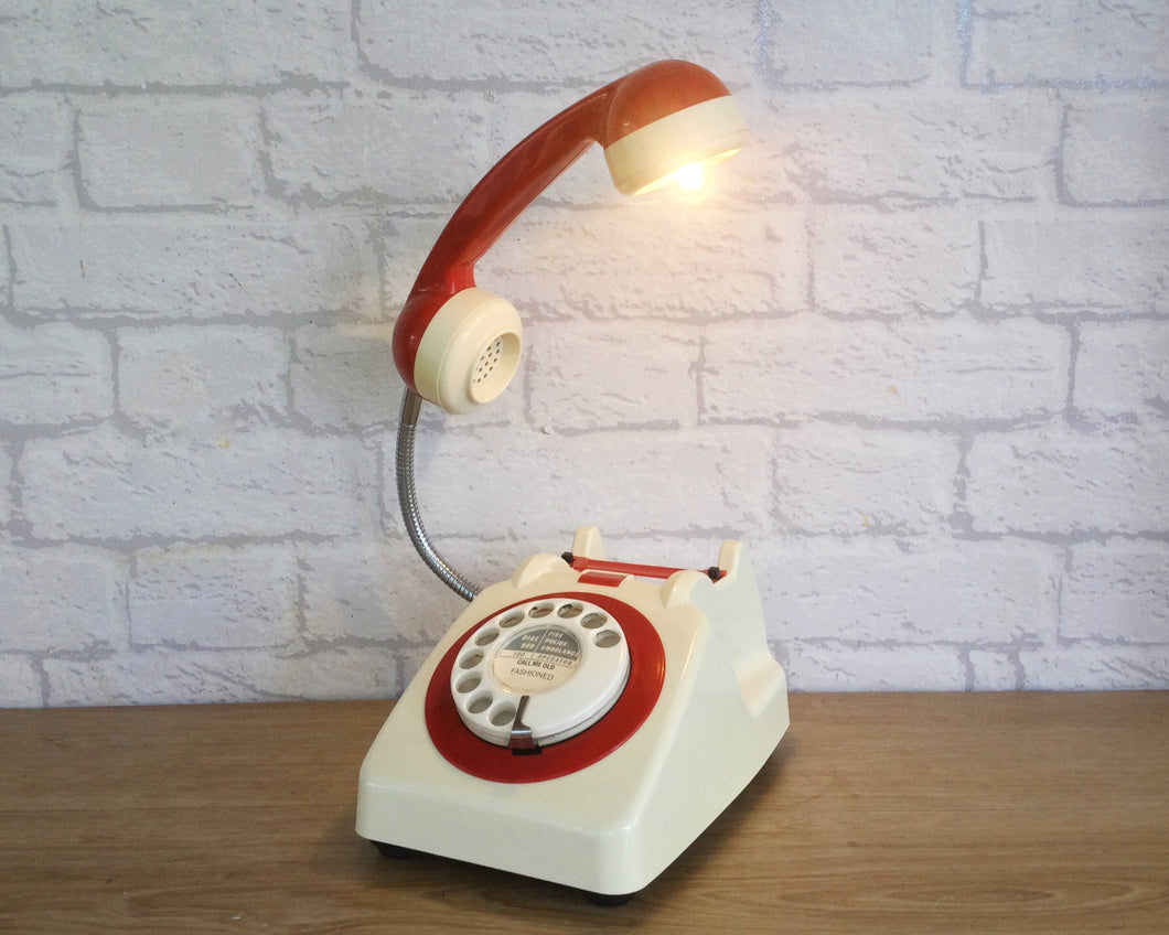 A quirky lamp made from a retro phone. The base of the lamp is a classic cream rotary phone with a cream dial & red dial ring. The red handset mounted on a flexible gooseneck has a small LED bulb in the receiver converting it into a fabulous lamp.