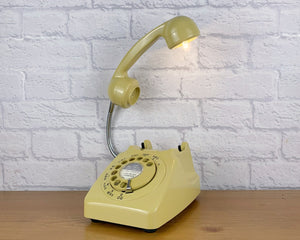 A quirky lamp made from a retro phone. The base of the lamp is a classic mustard rotary phone with a mustard dial & dial ring. The mustard handset mounted on a flexible gooseneck has a small LED bulb in the receiver converting it into a fabulous lamp