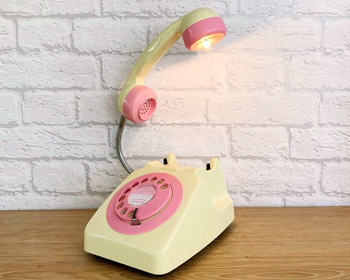 A quirky lamp made from a retro phone. The base of the lamp is a classic cream rotary phone with a pink dial & dial ring. The cream handset mounted on a flexible gooseneck has a small LED bulb in the receiver converting it into a fabulous lamp.