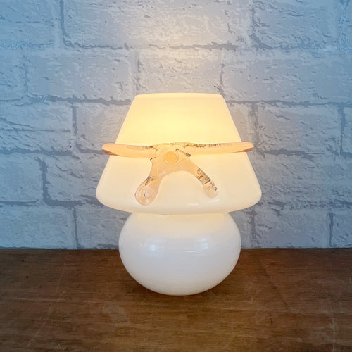 A 1970s vintage Murano blown glass mushroom lamp with a rounded white opaque base and shade. It features a translucent pink glass ribbon bow wrapped around the middle of the shade. Handmade in Italy, this is one of the rarer hard to find designs.