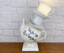 Load image into Gallery viewer, A wonky stacked teapot lamp, featuring a teapot at the base with “tea for two &amp; two for tea” written on it, topped by two tilted teacups and saucers. A charming and unique gift for any tea drinker, tea lover, or teapot collector.
